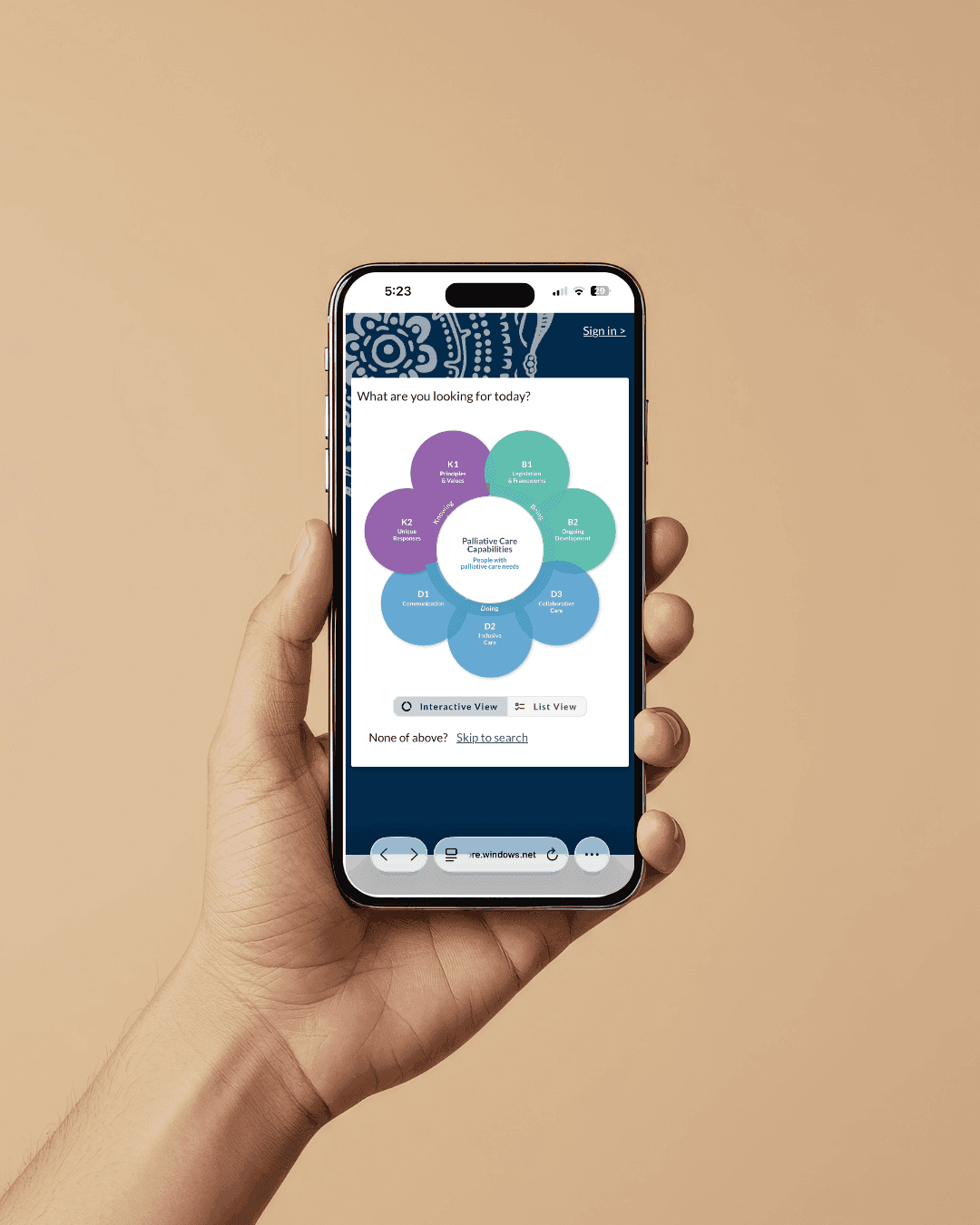 A hand holding a phone showing the PaCE capability wheel — eight coloured segments around a centre reading Palliative Care Capabilities, with Interactive View and List View tabs beneath.